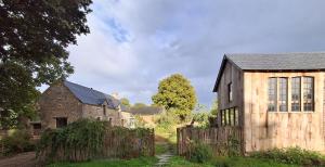 an old building with a fence next to a house at Le Temps du Coeur - TYNID in Saint-Ganton
