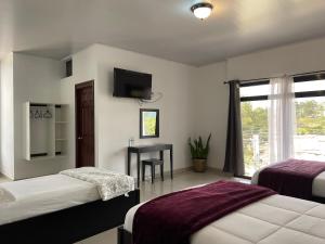 a bedroom with two beds and a desk with a television at Diesbu Hotel in Marcala