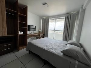 a bedroom with a bed and a desk and a window at Studio Easy West Flat in Mossoró
