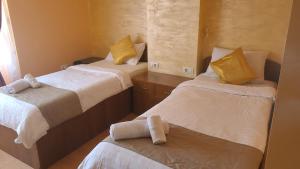 a room with two beds with white sheets and yellow pillows at Casa Heidi in Timişoara
