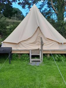 a large tent with a bench in the grass at St Mullins Glamping Bell Tent in Saint Mullins