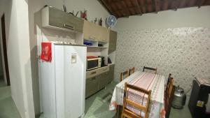 a kitchen with a white refrigerator and a table with chairs at Casinha no Sítio in Guaramiranga +6 photos