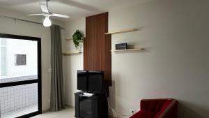 a living room with a tv and a red chair at Apartamento Satel Praia in Itanhaém