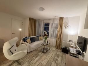 a living room with a white couch and a tv at Le Normandy 5star in Cadzand