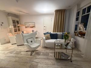 a living room with a white couch and chairs at Le Normandy 5star in Cadzand