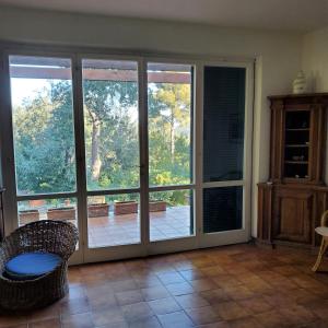 an empty room with sliding glass doors with a chair at Villa vista mare in Procchio +19 photos