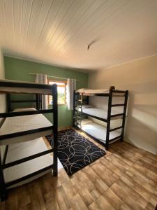 a room with three bunk beds and a rug at Hostel Canaã in Itanhandu