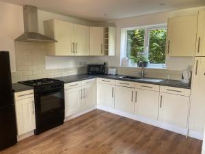 a kitchen with white cabinets and black appliances at Beechen Lodges in Bishops Waltham