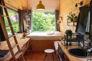 a tiny house with a window and a bed in it at Tiny house gite bucolique Brocéliande Hébergement insolite et centre bien être in Saint-Brieuc-de-Mauron