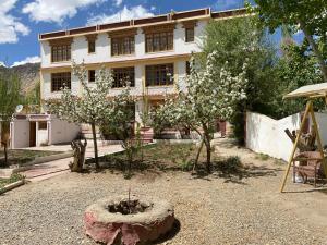 a building with a garden with flowering trees in front of it at Hotel Galaxy Ladakh in Leh