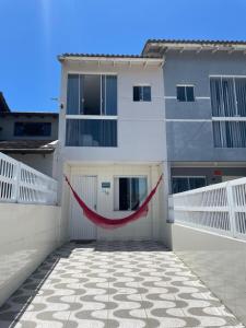 a white building with a red hammock in front of it at Ares de Salinas - 100 metros da praia in Cidreira