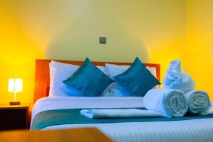 a bedroom with a bed with blue pillows and towels at Fort Arch Eco-Lodges in Fort Portal