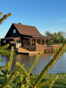 a house on a dock on a body of water at Pakarklių sodyba in Anykščiai