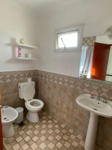 a bathroom with a toilet and two sinks and a window at Departamento zona centro in Villa María