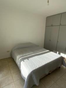 a bed in a bedroom with a white wall at Departamento zona centro in Villa María