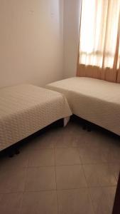 two beds sitting in a room with a window at Apartamento Macanal in Macanal