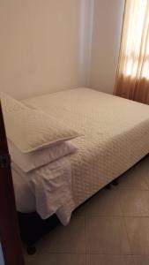 a bedroom with a bed with white sheets and a window at Apartamento Macanal in Macanal