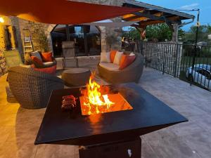 a fire pit on a patio with chairs and an umbrella at Le Mas Vivarés in Lablachère
