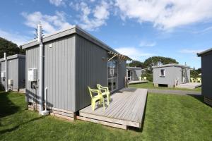 ein Haus mit einer Terrasse mit zwei Stühlen darauf in der Unterkunft Fitzroy Beach Holiday Park in New Plymouth