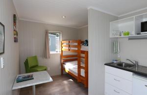 Habitación pequeña con litera y cocina en Fitzroy Beach Holiday Park, en New Plymouth