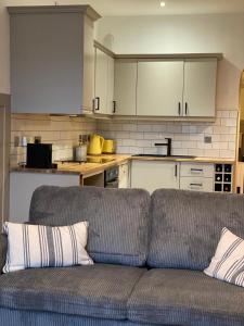 a living room with a couch in front of a kitchen at The Old Shop Apartment in Rathmullan