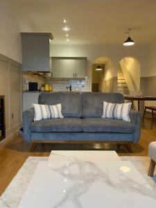 a living room with a blue couch and a kitchen at The Old Shop Apartment in Rathmullan