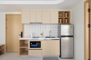 a kitchen with white cabinets and a stainless steel refrigerator at Premium 2BR near Kamala Beach, Pool, Gym & Shuttle Bus in Phuket