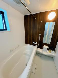 a white bath tub in a bathroom with a window at HB Home TOKYO in Tokyo