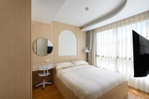 a bedroom with a bed and a flat screen tv at Premium 2BR near Kamala Beach, Pool, Gym & Shuttle Bus in Phuket