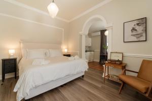 a bedroom with a large white bed and a chair at Story Haus in Stellenbosch
