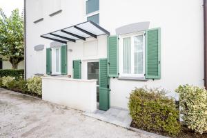 a white house with green shutters and a porch at Le Sabbie B&B - Camere in villino a 50mt dal mare in Riccione +15 photos