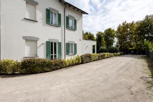 a white house with green windows and a driveway at Le Sabbie B&B - Camere in villino a 50mt dal mare in Riccione