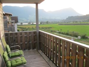 a balcony with two chairs and a view of a field at Holz100 Zimmer mit Rigiblick in Steinen