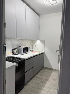 a white kitchen with a microwave and a stove at AeroHome Moldova- TAXI-PARKING ! in Chişinău