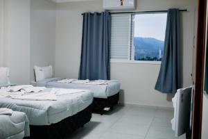 two beds in a room with a window at Hotel Beirut in Aparecida