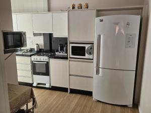 a kitchen with white appliances and a white refrigerator at Apartamento Beira-mar praia centro itapema in Itapema