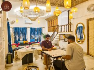 two men sitting at a table in a room at Ghotul Hostel & Homestay in Guwahati