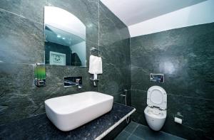 a bathroom with a sink and a toilet and a mirror at Raj Villas by Jomotel - A Riverside Retreat in Banjār +22 photos