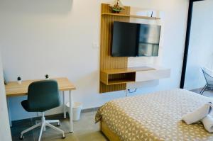 a bedroom with a bed and a desk and a television at Samaia Loft in Santa Marta