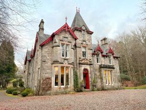 an old stone house with a red door at Birchwood Pitlochry in Pitlochry