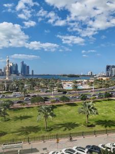 a park with palm trees and a city in the background at King bed sea view in Sharjah