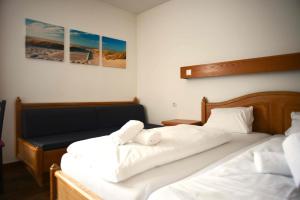 a bedroom with two beds with white sheets at Hotel Andreas Hofer in Dornbirn