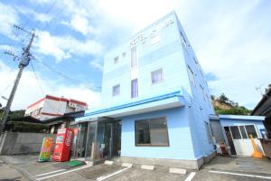 a blue and white building in a parking lot at Hotel Auberge in Yakushima