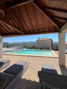 a large swimming pool with a wooden pergola at Daisy Country House in Lousada