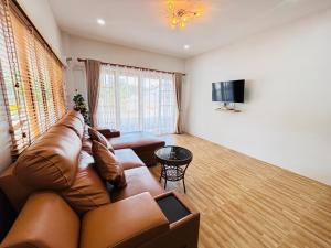a living room with a leather couch and a television at AAA villa Aonang Krabi in Ao Nang 