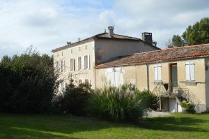 an old building in a yard with a grass field at La Vieille Distillerie in Le Tâtre