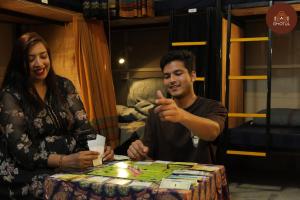 a man and a woman sitting at a table playing a game at Ghotul Hostel & Homestay in Guwahati