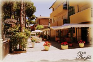 a street with tables and umbrellas and flowers in pots at Hotel Furga B&B in Cervia