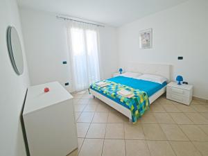 a white bedroom with a bed and a refrigerator at Residence Lucrezia in Nardò