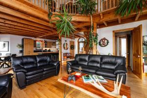 a living room with black leather couches and a table at Havre sur la Baie in Baie-Saint-Paul